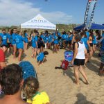 A large group of people gathered on a sunny beach for an event.