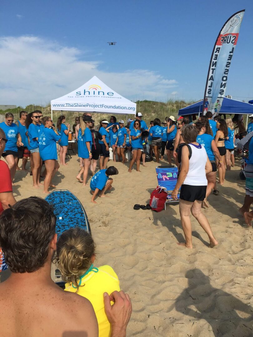 A large group of people gathered on a sunny beach for an event.