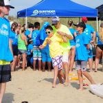A man teaches a boy to surf on the beach at a surf camp.