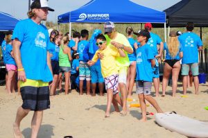 A man teaches a boy to surf on the beach at a surf camp.