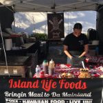 Vendor prepares Hawaiian food at Island Life Foods stall.