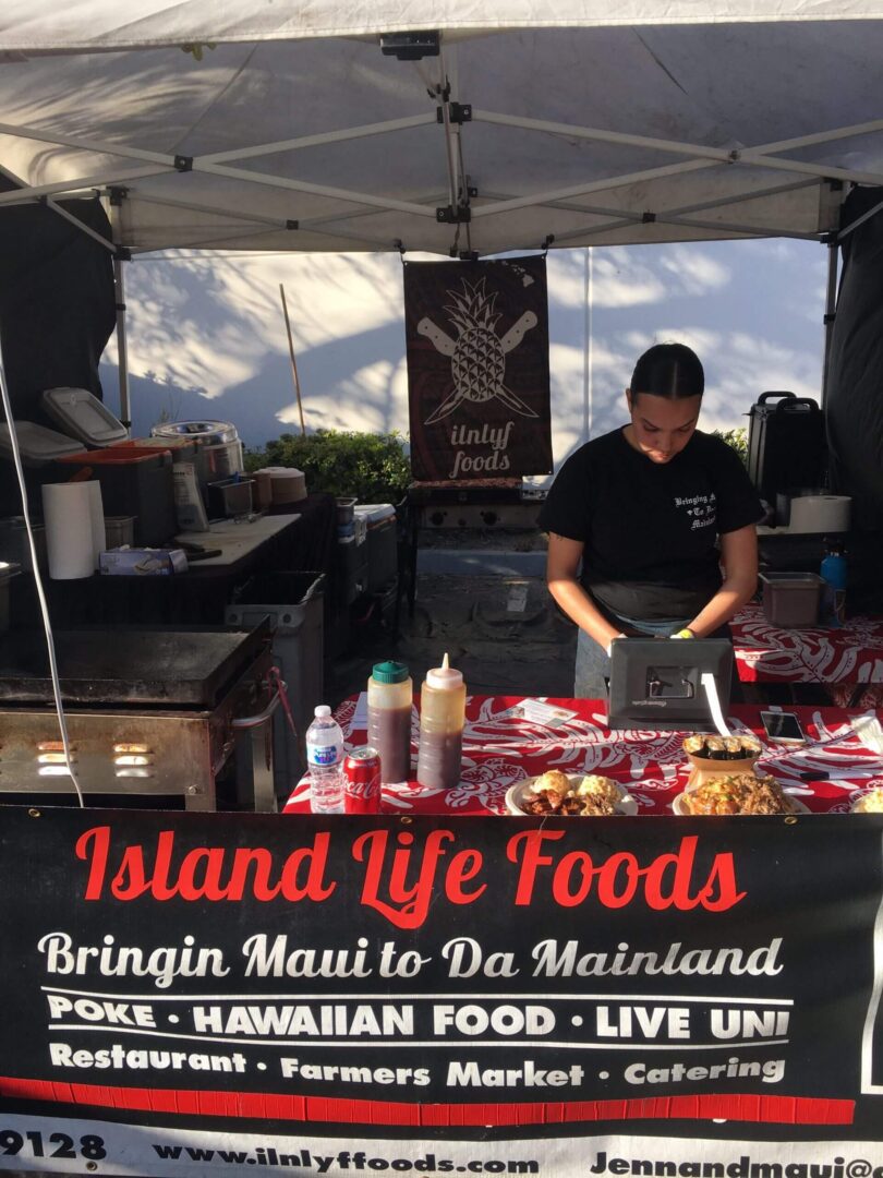 Vendor prepares Hawaiian food at Island Life Foods stall.