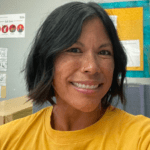 Smiling woman with short dark hair wearing a yellow shirt.