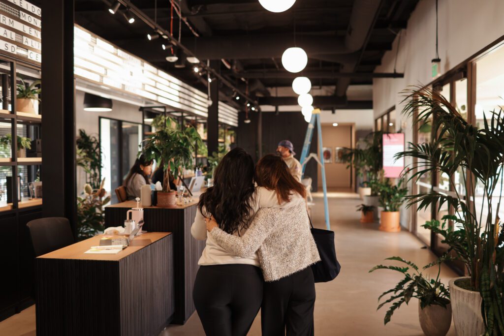Two friends walking arm-in-arm inside
