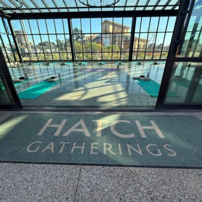 View of a patio with "Hatch Gatherings" written on the floor and a fenced pool outside.