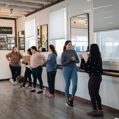 Students chatting along barre in studio